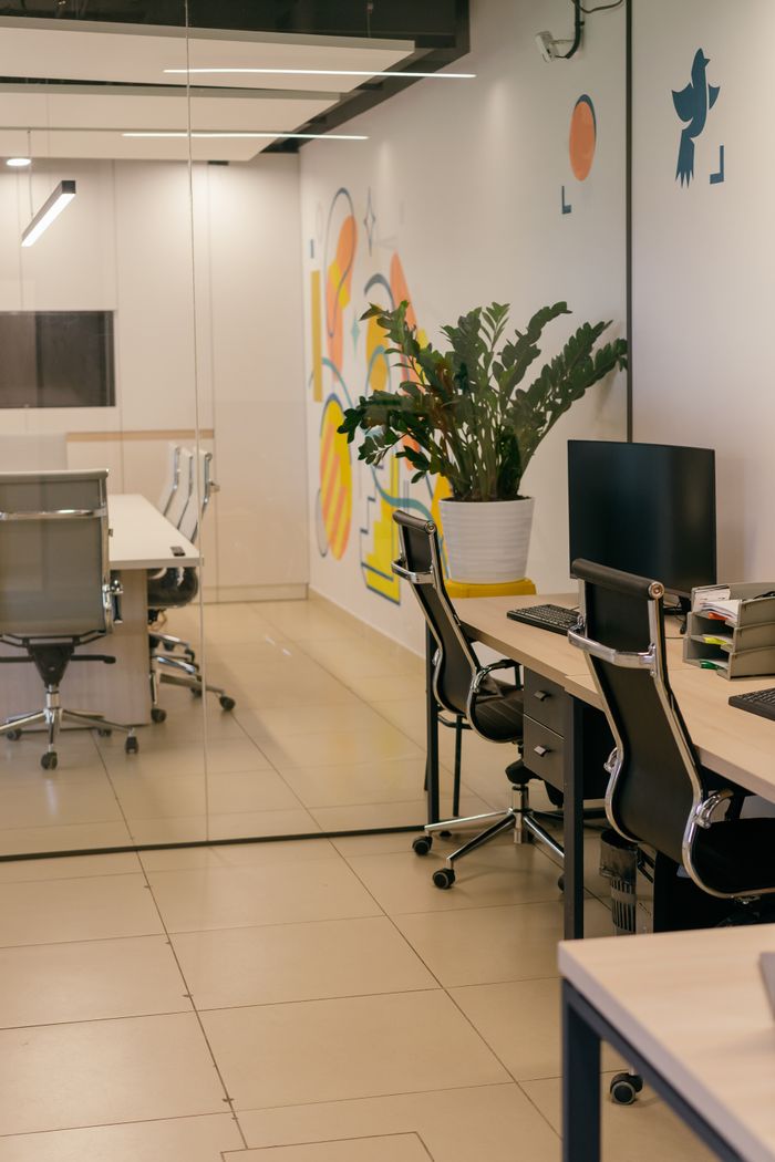 Intérieur de bureau moderne et spacieux avec cloisons en verre, mobilier design et œuvres murales colorées.